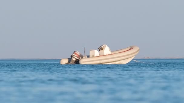 Paysage marin avec surface ondulée d'eau de mer bleue avec hors-bord blanc sur l'ancre flottant sur des vagues calmes. — Video