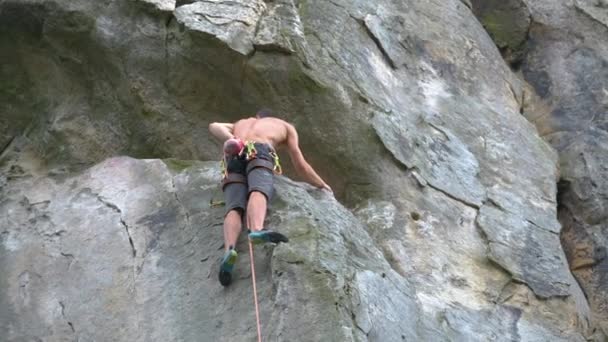 強い男性登山岩の山の急な壁を登る。難しいルートを克服するスポーツマン。極端なスポーツ趣味の概念に従事. — ストック動画