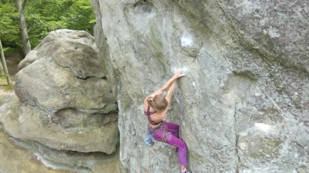 Entschlossene Bergsteigerin, die die steile Wand des felsigen Berges hinaufklettert. Sportlerin bewältigt schwierige Strecke. Extremsport und Kletterhobby-Konzept. — Stockvideo