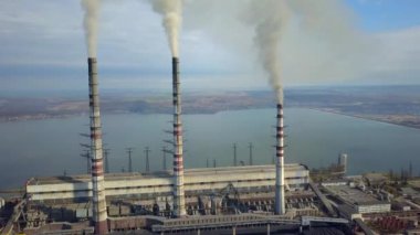 Kömür santralinden gelen gri dumanlı yüksek baca borularının havadan görüntüsü. Fosil yakıtla elektrik üretimi