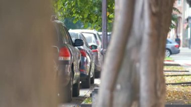 Sokak kenarında park halindeki arabalarla şehir trafiği.
