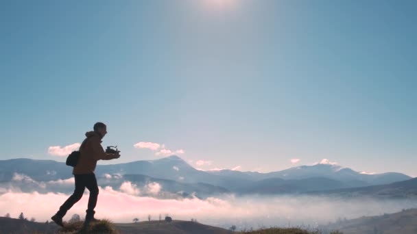 Sırt çantalı bir fotoğrafçının silüeti sonbahar dağlarında dijital kamerayla sabah manzarasının fotoğraflarını çekiyor.. — Stok video