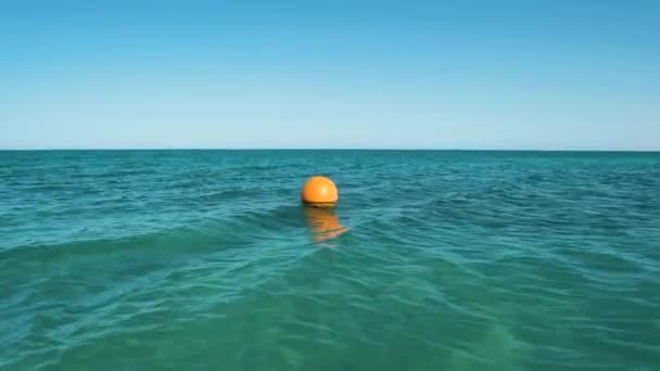 Bouée orange flottant sur les vagues de surface de la mer. Concept de sécurité humaine. — Video
