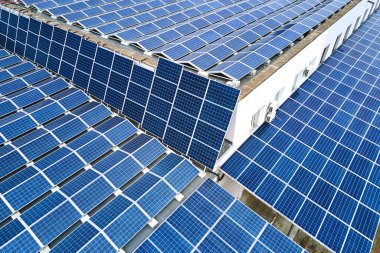 Sanayi binasının çatısına yeşil ekolojik elektrik üretmek için monte edilmiş mavi fotovoltaik panelli güneş enerjisi santralinin hava görüntüsü. Sürdürülebilir enerji konsepti üretimi.