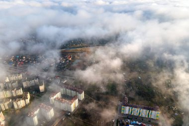 Modern şehrin üzerinde yüksek binaları olan kabarık beyaz bulutların üst hava manzarası.