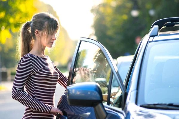 街の通りで車の横に立つ暖かい夏の日を楽しむ幸せな若い女性ドライバー 旅行と休暇のコンセプト — ストック写真