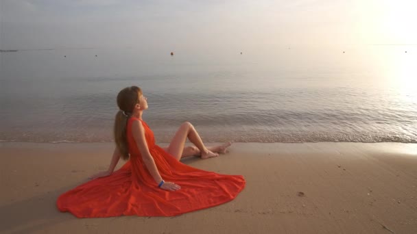 Jeune femme heureuse en robe rouge se détendre sur la plage de sable fin au bord de la mer profitant matin tropical chaud. — Video