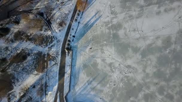 Drone widok z lotu ptaka człowieka leżącego na zamarzniętym jeziorze w zimie w mieście. — Wideo stockowe