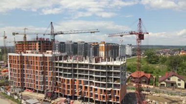 İnşaat halindeki yüksek beton binadaki vinçler ve profesyonel işçiler. Emlak geliştirme konsepti. Kyiv, Ukrayna - 21 Temmuz 2021