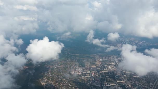 Vista aerea dal finestrino dell'aeroplano ad alta quota della città lontana coperta da nuvole cumulus gonfie che si formano prima della tempesta di pioggia — Video Stock