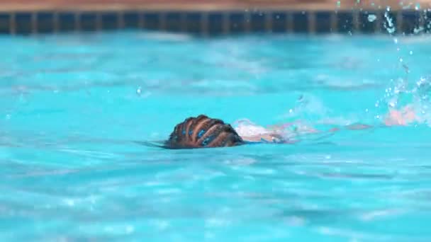 Bambina che cerca di nuotare in piscina con acqua limpida blu. Concetto attività estive — Video Stock