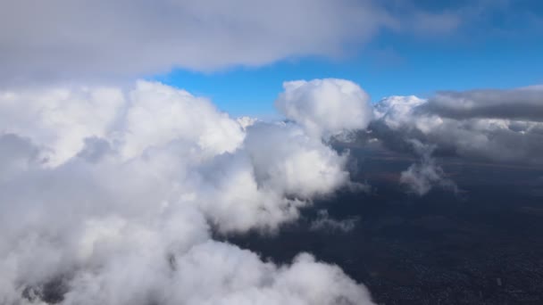Вид с воздуха из окна самолета на большой высоте земли, покрытый белыми кучевыми облаками — стоковое видео