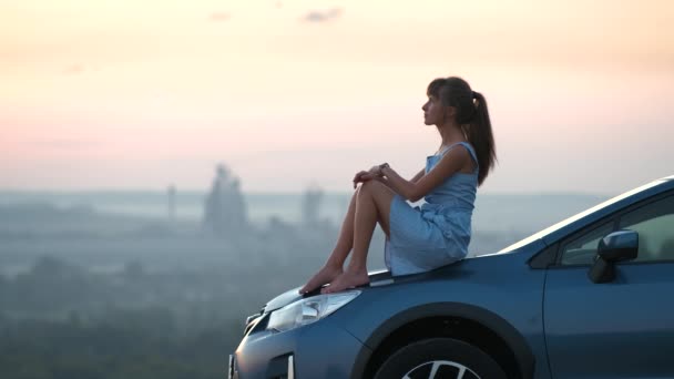 Felice giovane donna autista in abito blu godendo di calda serata estiva posa sul suo cofano dell'auto. Viaggiare e concetto di vacanza — Video Stock