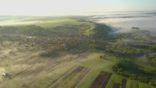 Légi kilátás reggel több mint falusi házak zöld tavaszi dombok — Stock videók