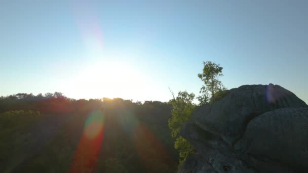 Lebendiger nebliger Abend über dunklen Waldbäumen und großen Felsformationen bei strahlendem Sommersonnenuntergang. Erstaunliche Landschaft wilder Wälder in der Abenddämmerung — Stockvideo