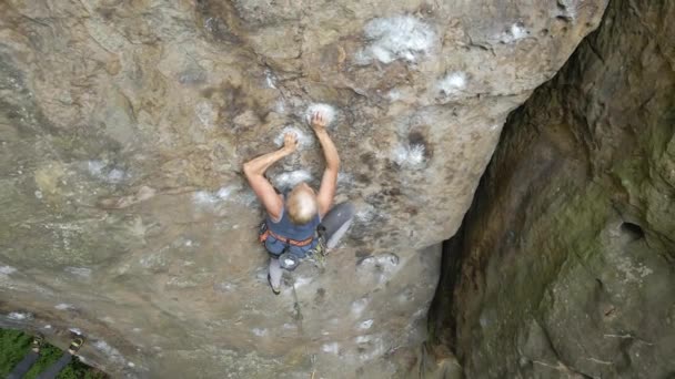 Mujer joven escalando empinada pared de montaña rocosa. Niña escaladora supera ruta desafiante. Participar en el concepto de deporte extremo — Vídeo de stock