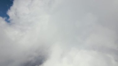 Dünya 'nın yüksek irtifasındaki uçak penceresinden hava manzarası beyaz kabarık kümülüs bulutlarıyla kaplı.