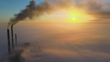 Kömür santralinin hava manzarası siyah dumanlı yüksek borular gün batımında atmosferi kirletiyor
