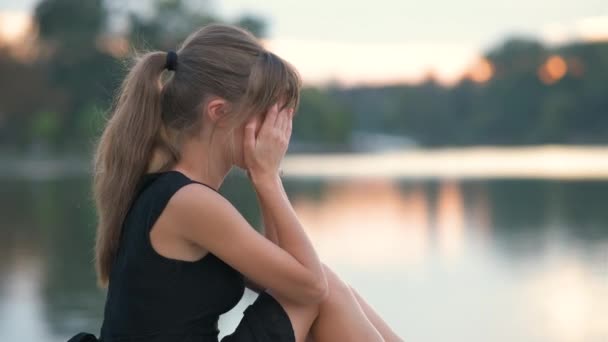 Jovem deprimida sentada sozinha ao ar livre chorando tristemente. Conceito de depressão e emoções — Vídeo de Stock