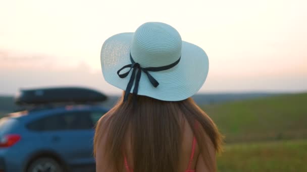 Mladá žena cestovatel stojí sám u svého auta na zelené louce během výletu v létě. Cestování podle koncepce vozidla — Stock video