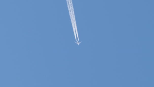 Oddalony odrzutowiec pasażerski lecący na dużej wysokości na bezchmurnym błękitnym niebie zostawiający za sobą biały ślad dymu. Koncepcja transportu lotniczego — Wideo stockowe