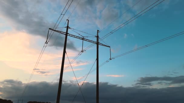 Donker silhouet van hoogspanningstoren met elektrische leidingen bij zonsondergang. Overdracht van elektriciteit — Stockvideo