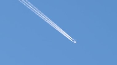 Mesafeli yolcu jet uçağı açık mavi gökyüzünde yüksek irtifada uçarken ardında beyaz duman izi bırakıyor. Hava taşımacılığı kavramı