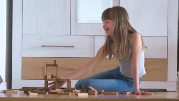 Glad barn flicka spelar spel stapling trä leksaksblock i hög lugg struktur. Handrörelsekontroll och uppbyggnad av beräkningsfärdigheter — Stockvideo