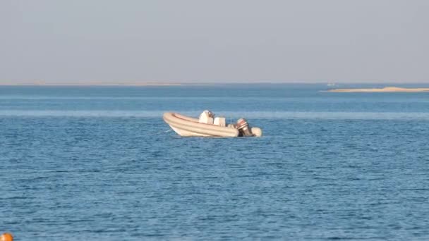 Laut dengan permukaan riak air laut biru dengan speedboat putih pada jangkar mengambang di gelombang tenang — Stok Video