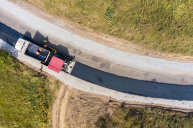 Asfalt döşeme makineleriyle yeni yol yapımının havadan görüntüsü.
