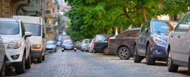 Sokak kenarında park halindeki arabalarla şehir trafiği.