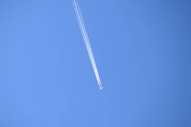 Mesafeli yolcu jet uçağı açık mavi gökyüzünde yüksek irtifada uçarken ardında beyaz duman izi bırakıyor. Hava taşımacılığı kavramı.