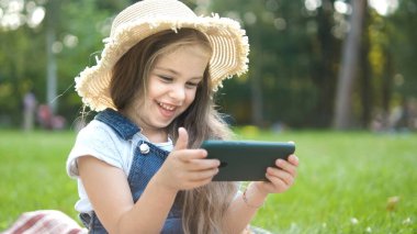 Mutlu gülümseyen kız yazın açık havada cep telefonuna bakıyor..