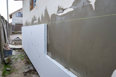 Termal koruma için ev cephesi duvarına köpük yalıtım çarşafları kurulumu.
