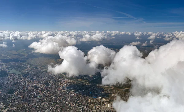 暴風雨前に形成されたパフィー積雲に覆われた遠くの都市の高高度での航空機の窓からの眺め — ストック写真