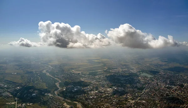 白いパフィーの積雲に覆われた遠くの都市の高高度での飛行機の窓からの空の景色 — ストック写真