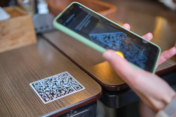 Konuk elin restoranda yemek sipariş ederken çevrimiçi menü için qr kodunu cep telefonuyla taraması.