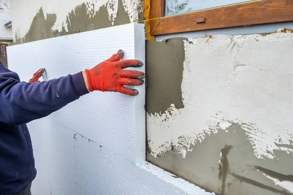 建筑工人在房屋正面墙壁上安装泡沫隔热板以进行保温 — 图库照片