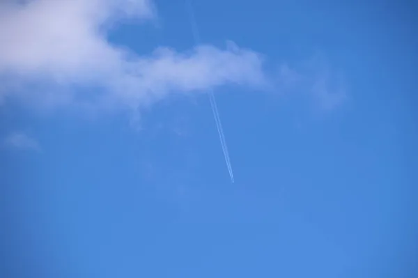 遠くの旅客機は白い雲が後ろの輪郭の煙の跡を残す青い空の高い高度で飛んでいる 航空旅行の概念 — ストック写真