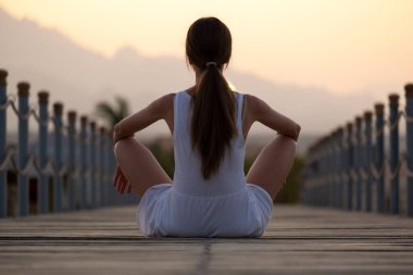 Günlük kıyafetlerle genç bayan turist deniz kıyısında güneşli bir akşamın tadını çıkarıyor. Yaz tatilleri ve seyahat konsepti.