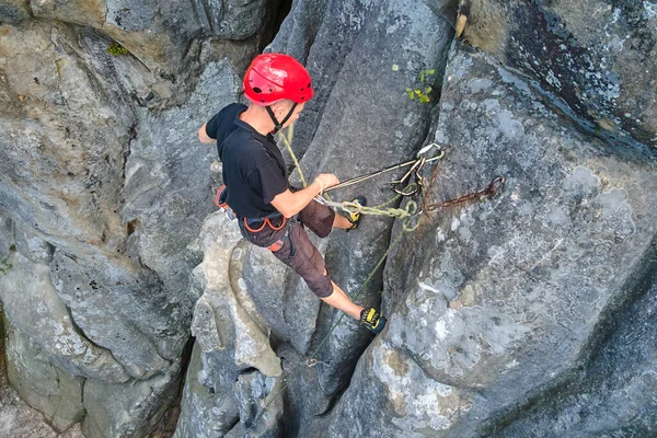 若い男岩の山の急な壁を登る 男性登山者は困難なルートを克服します 極端なスポーツの概念に従事 — ストック写真