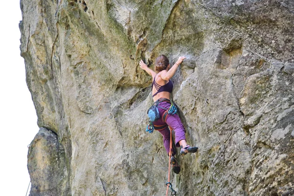 若い女性岩の山の急な壁を登る 登山家は困難な道を克服します 極端なスポーツの概念に従事 — ストック写真