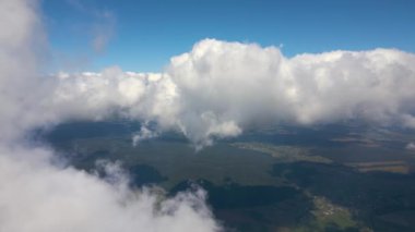 Dünya 'nın yüksek irtifasındaki uçak penceresinden hava manzarası beyaz kabarık kümülüs bulutlarıyla kaplı..