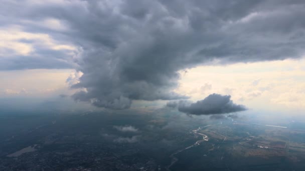 Aerial view from airplane window at high altitude of distant city covered with puffy cumulus clouds forming before rainstorm. — Stock Video