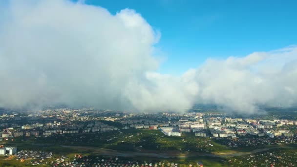 Aerial view from high altitude of distant city covered with puffy cumulus clouds forming before rainstorm. — Stock Video