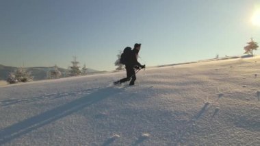 Soğuk kış sabahında sırt çantalı gezginin karlı dağ yamacına yürüyüşünün hava görüntüsü..