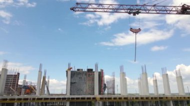 İnşaat halindeki yüksek beton binadaki vinç ve işçiler. Gayrimenkul geliştirme kavramı.