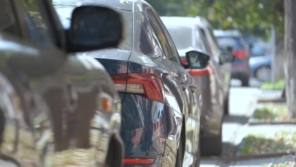 Stadstrafik med bilar parkerade i linje på gatan sida. — Stockvideo