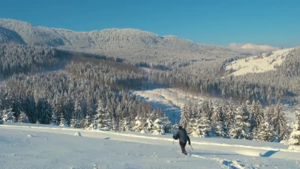 Man backpacker wandelen besneeuwde berg heuvel op koude winterdag. — Stockvideo