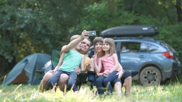 Padres y sus hijos sentados juntos en el camping y tomando selfie con teléfono móvil. — Vídeos de Stock